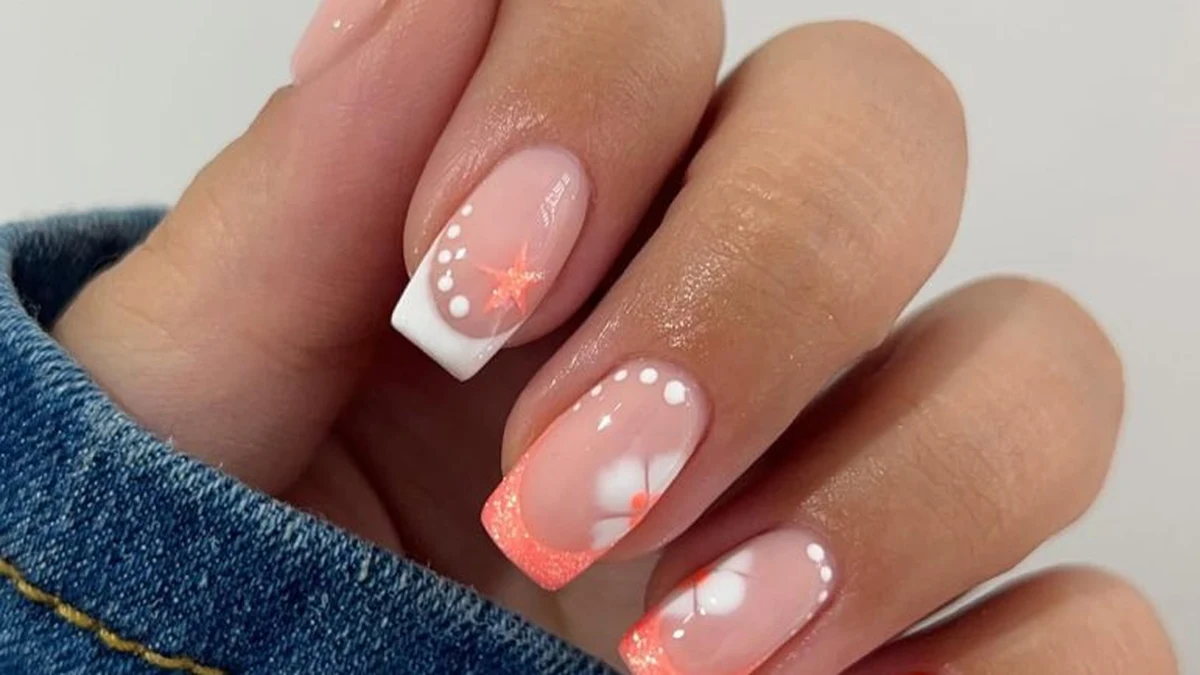 French tips corail avec fleurs blanches délicates sur ongles naturels